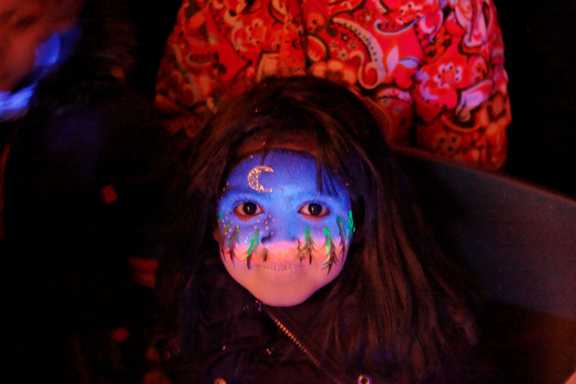 A child with a moonlit forest painted on her face